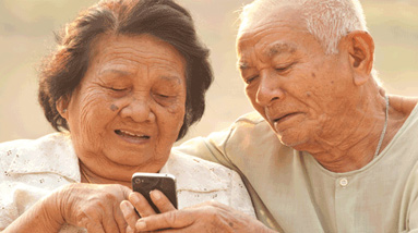 Photo of two people smiling and looking at a mobile phone